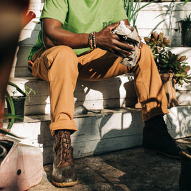 fit model sitting down in garden wearing The Carpenter Pant in Cedar Boss Duck