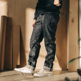 fit model leaning against the wall wearing The Democratic Jean in Kuroki Welterweight Slub