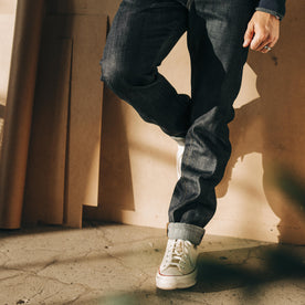 fit model leaning against the wall wearing The Slim Jean in Kuroki Welterweight Slub