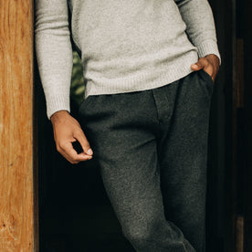 fit model standing against a wooden doorframe in The Weekend Pant in Coal Double Knit