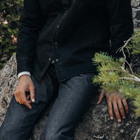 fit model sitting on a rock in The Slim Jean in Cone Mills Cordura Denim