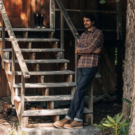 fit model leaning against some stairs in The Utility Shirt in Caramel Jaspe Herringbone Plaid