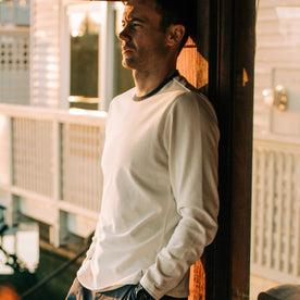 fit model wearing The Heavy Bag Long Sleeve in Natural, leaning against wall