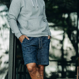 our fit model wearing The Après Short in Indigo Slub—wearing a hoodie early in the morning, cropped shot with hands in pocket