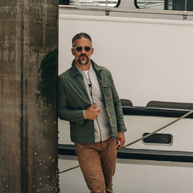 fit model wearing The Lombardi Jacket in Olive Dry Wax, standing on dock