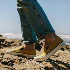 fit model wearing The Sano Slip-On in Gold Boss Duck, walking on coast