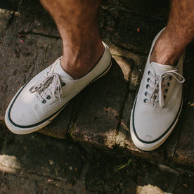 fit model wearing The Vista Sneaker in Natural Boss Duck, standing on stone stairway