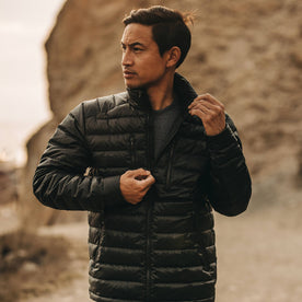 our fit model wearing The Taylor Stitch x Mission Workshop Farallon Jacket in Black—looking left on beach