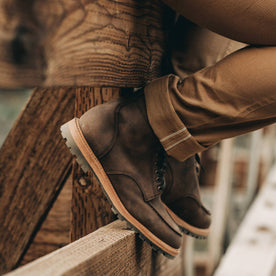 our fit model wearing The Scout Boot in Espresso Grizzly—sitting on fence