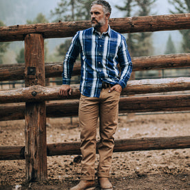 fit model wearing The Democratic All Day Pant in Rustic Oak Organic Selvage, near fence